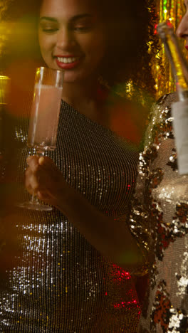 Vertical-Video-Of-Two-Women-In-Nightclub-Bar-Or-Disco-Having-Champagne-Poured-From-Bottle